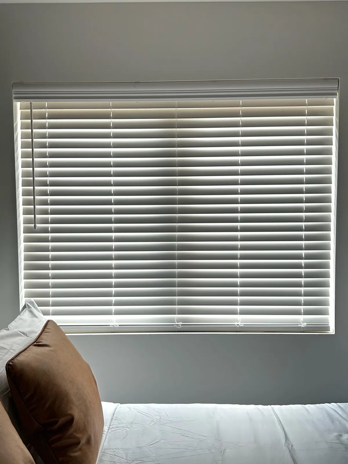 White faux wood blinds over a bed in a Dallas short-term rental unit