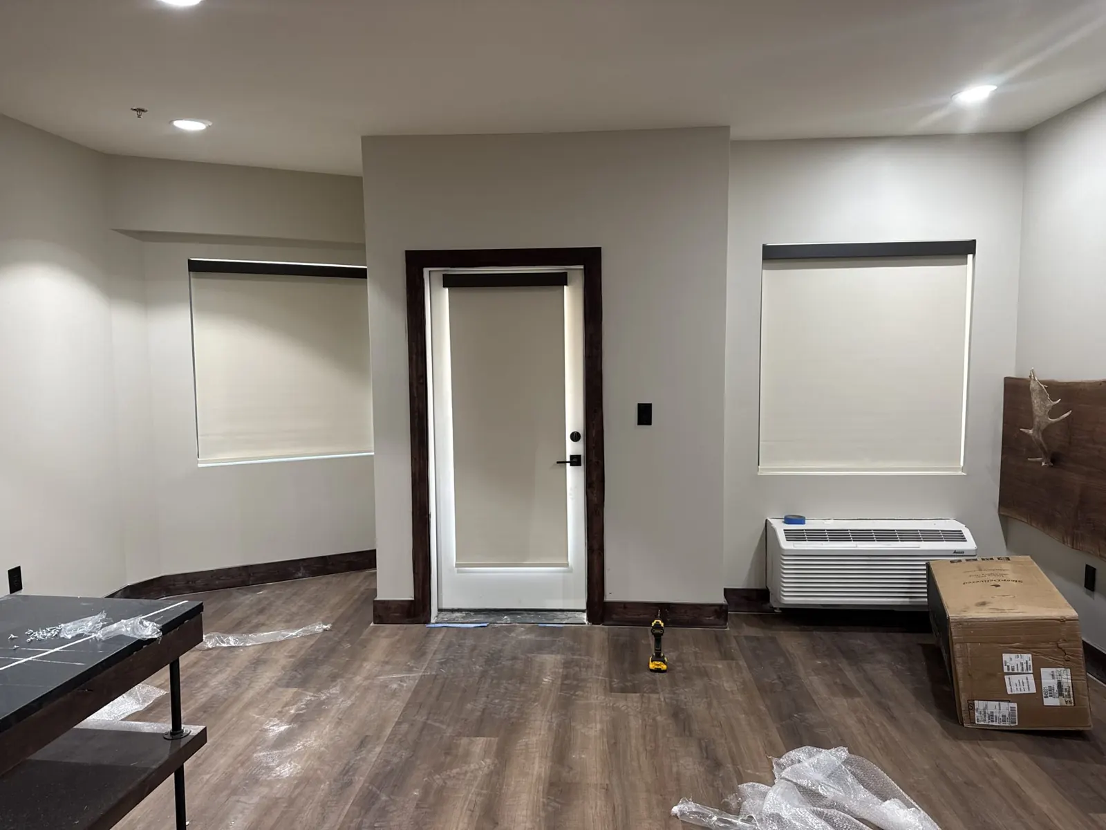 Off-white roller shades on two windows and a door in a hunting lodge room, Eustace, TX