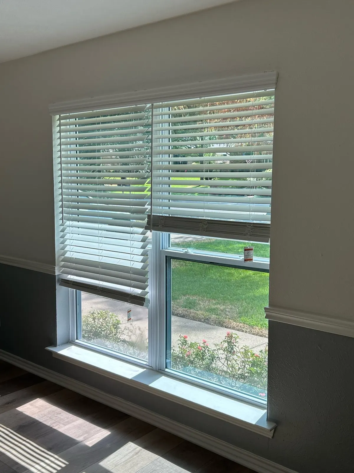 White faux wood blinds inside mounted on a double-hung window in an Irving, TX home
