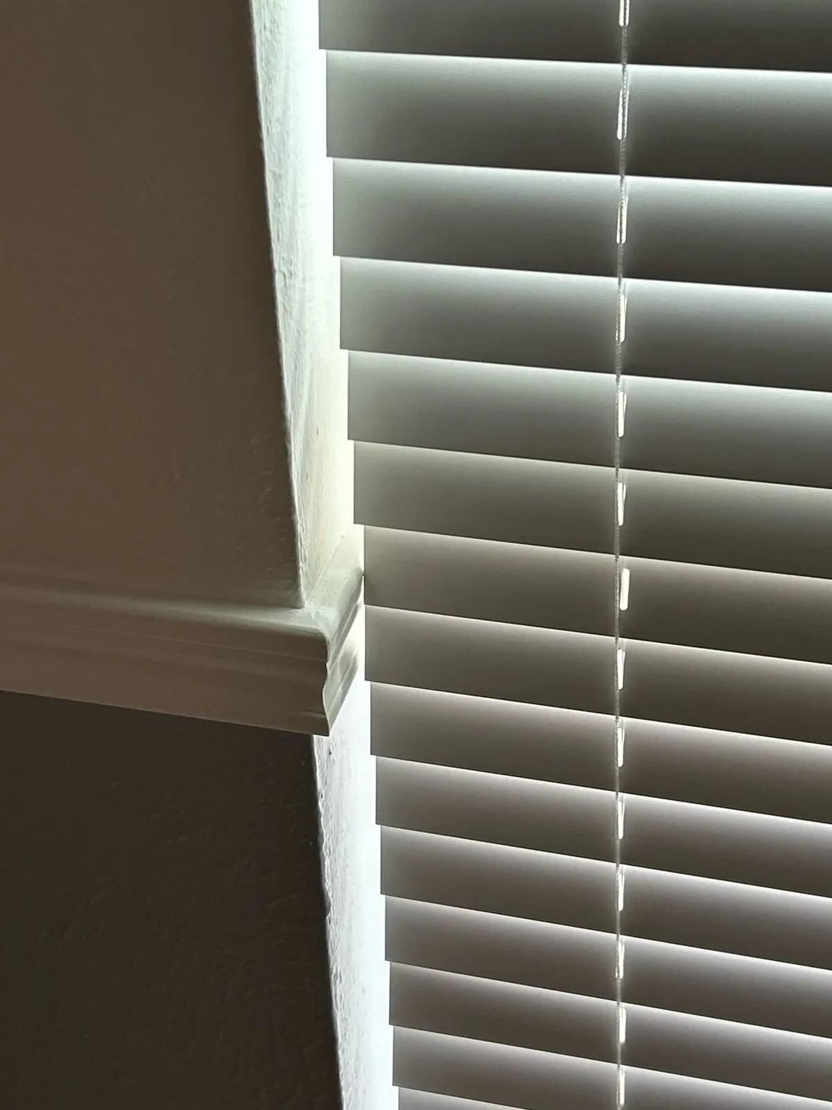 Close-up of white faux wood blind slats inside the window frame