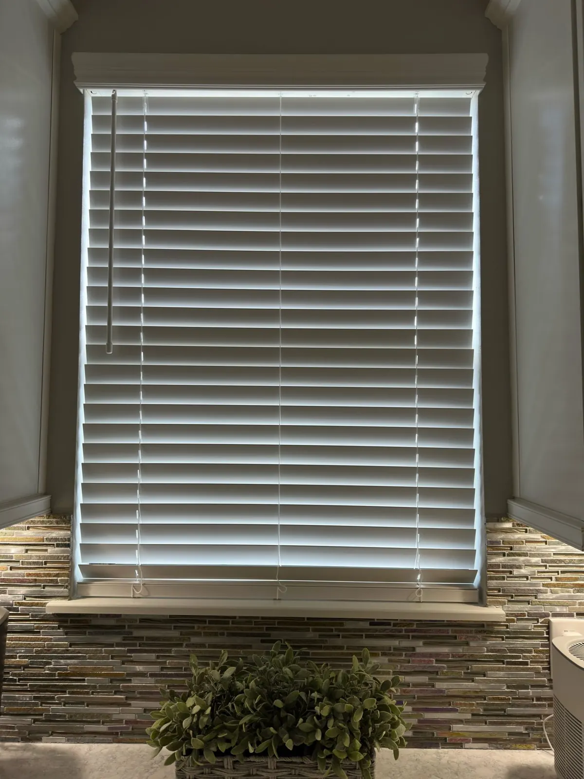 White faux wood blinds on a window above a stone ledge in a Tampa, FL home