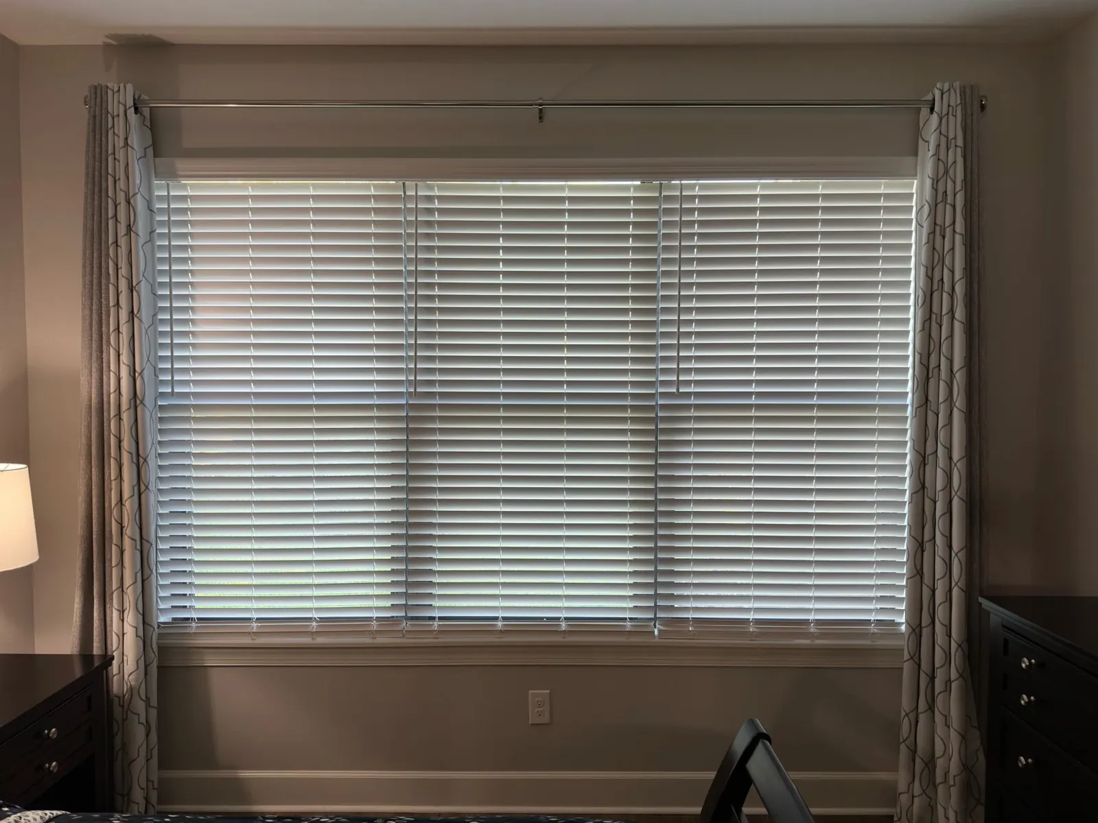 White faux wood blinds on a wide window with curtains in Tampa, FL